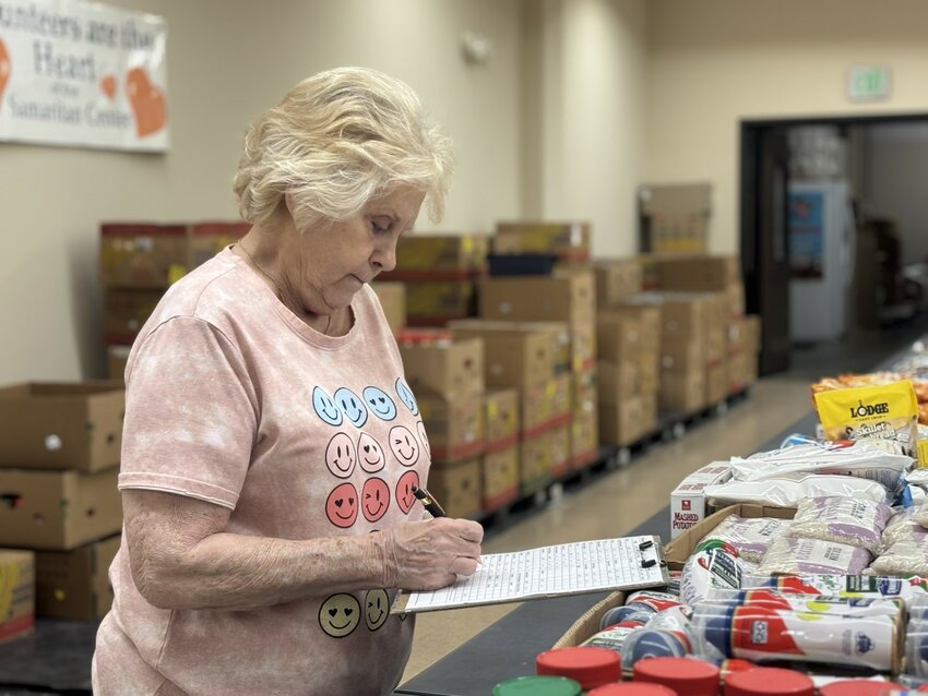 Willma Hutsell is a volunteer helping an elderly couple find the food they need.