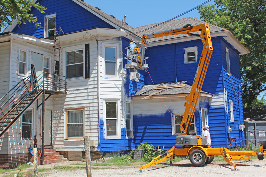 GETTING A LIFT, Bryan Goodson worked the bucket truck while a crew member applied paint to the apartment complex on the corner of Third and Ohio Streets in Clinton.