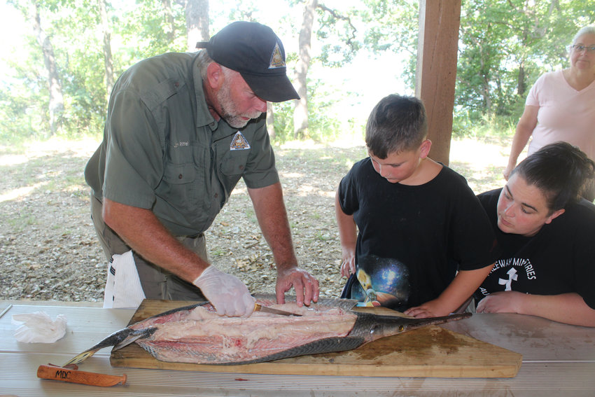 Rittel shows Alissa Taylor and son Trevor of Fair Grove the art of filleting the gar meat off the ribcage.