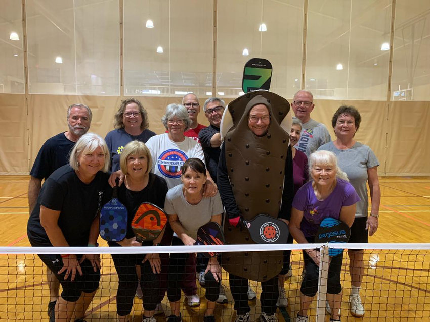 LOCAL PICKLEBALLERS at the Community Center stopped for a photo on Halloween, mainly to give Mark Parker a chance to show off his Ice Cream sandwich costume. Back row: Dan Davenport, Amy Michael, Marlene Martin, Tim Komer, Kevin Sullivan, Cathy Sullivan, Gene Henry, and Nancy Summers. Front row: Donna Jolley, Carlene Lowe, Enid Kelsey, Mark Parker (in costume), and Sheila Bourland. There are several groups that play the popular sport in town. Newbies are always welcome. Check out their Facebook page. Photo by Irene Komer