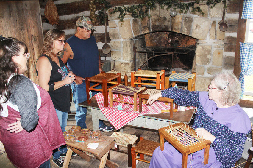 CONTINUING AN ANCIENT CRAFT, Diana Clark demonstrated seat caning on small stools in the kitchen of the dog-trot cabin at Old Settler&rsquo;s Day.