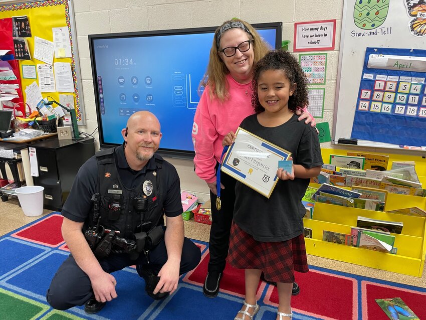 LIVING UP TO HER NAME, Myracle Fitzpatrick alerted Benton County 911 that her mother was in distress. Myracle was recognized with a reception at North Elementary where Warsaw Police Sgt. Tony Helms  and Dispatcher Karmen Smith presented the 6-year old with a medal and plaque.
