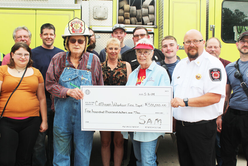 MAKING A MAJOR CONTRIBUTION to Calhoun, Sam Sloan and his wife Jan presented the Calhoun Fire Department with a donation of $500,000. Chief Mark Hardin presented Mr. Sloan with an honorary fire chief helmet during the check presentation.