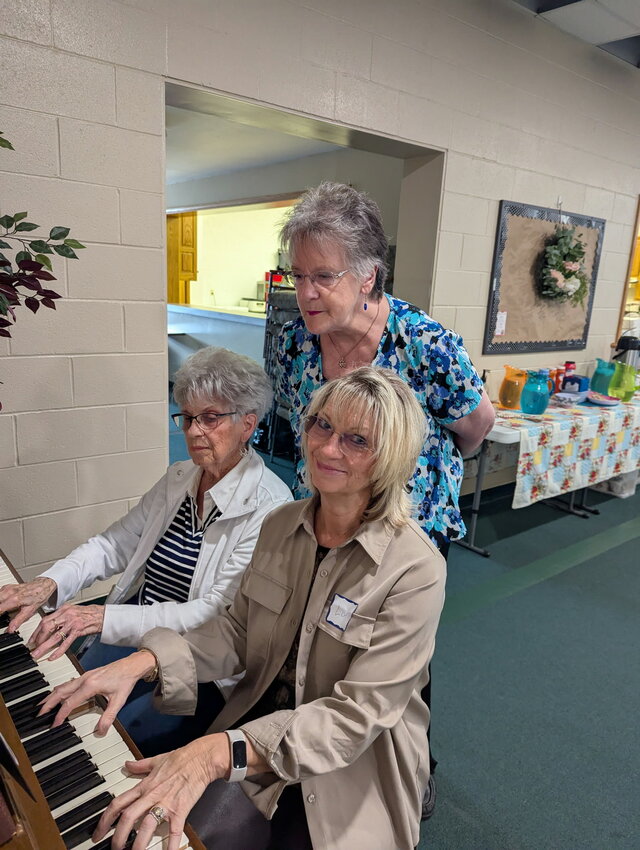 Playing the piano at a CWC luncheon, is Lisa Gurley, right, and her mother, Carol Rucker, while Jean Dennis looking on.