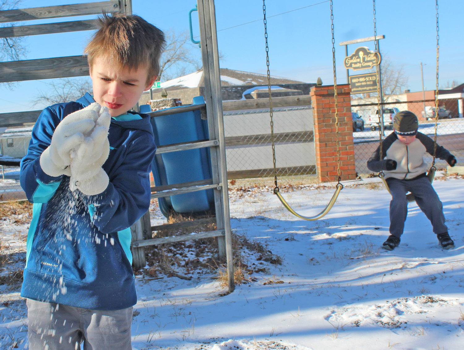 Matthew Aldridge looks a sparkles in the snow, while older
brother Noah swings, on January 6, on the playground by
the old Holy Rosary Catholic Church on 2nd Street in
Clinton.