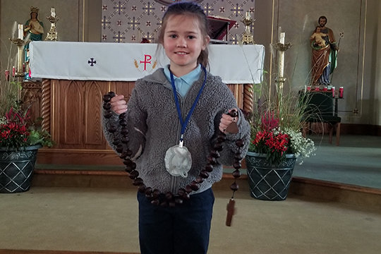 Third-grader Lily Bosworth, daughter of Julie Bosworth, displays the buckeye rosary she won this year as part of the annual Month of the Rosary observance at St. Joseph School in Martinsburg.