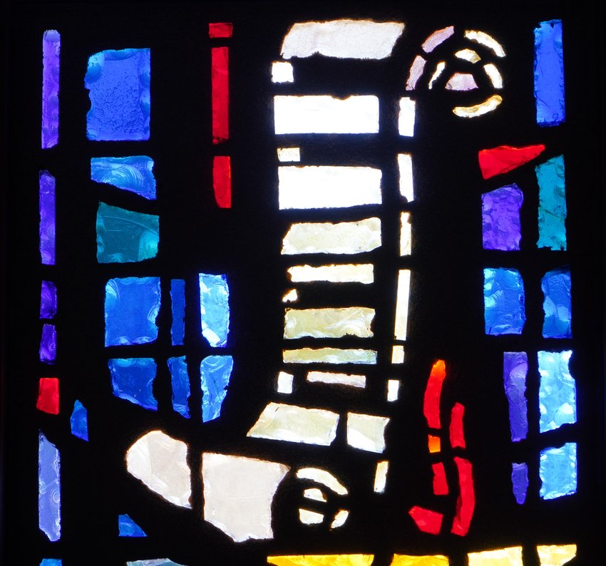 A scroll and lamp, symbolizing the preaching and teaching mission of the Church and its priests, are depicted in stained glass in the chapel of the Cathedral of St. Joseph in Jefferson City.