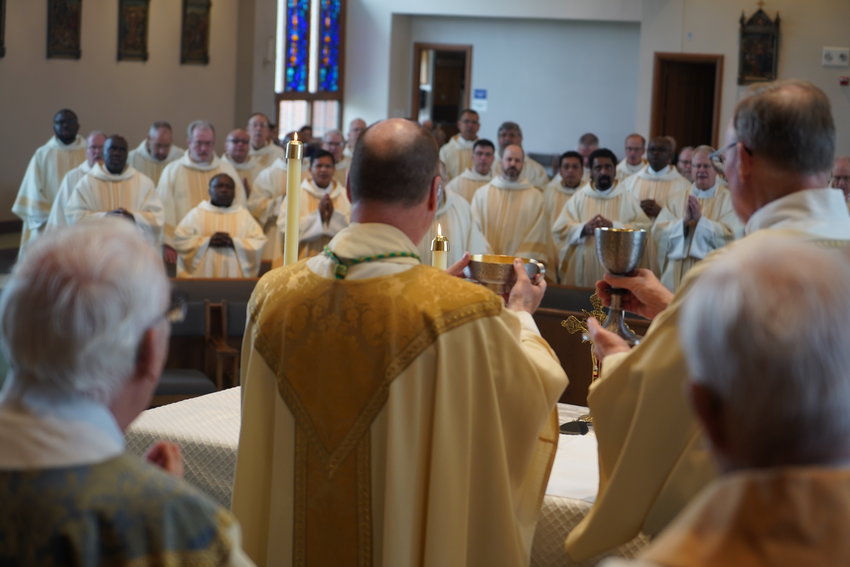 Bishop W. Shawn McKnight, assisted by Deacon John Schwartze, elevates the Most Blessed Sacrament while he and priests of the diocese pray the Doxology together during the Chrism Mass on April 12 in St. Andrew Church in Holts Summit. &mdash; Photo by Jay Nies