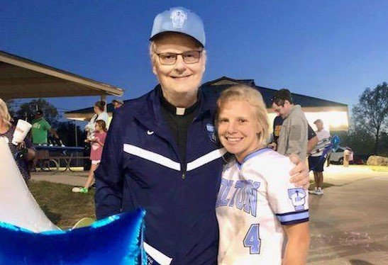 Father Michael Coleman congratulates Sophie Angel, a member of the Fr. Tolton Regional Catholic High School varsity softball team, after a victorious Senior Night game in Columbia.