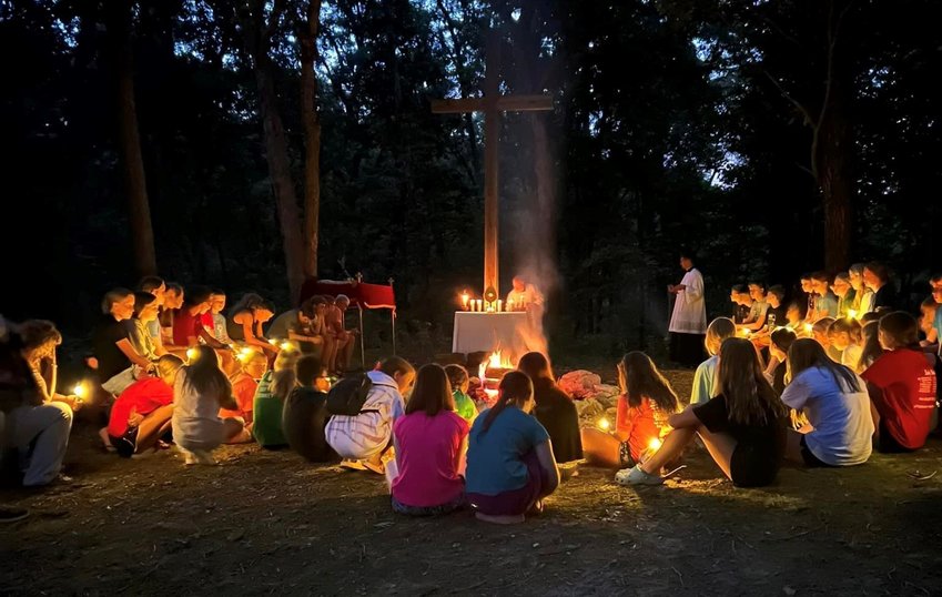 Participants in the Camp Tolton Catholic camp for young people gather for Adoration of the Most Blessed Sacrament by firelight following a Eucharistic procession to a wooded area at Camp Jo&rsquo;Ota in Clarence.