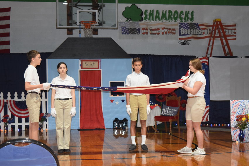 Middle school students at Holy Family School in Hannibal demonstrate the folding of the U.S. Flag and explain the significance of each of the 13 folds during the school&rsquo;s veterans celebration the day before Veterans Day.