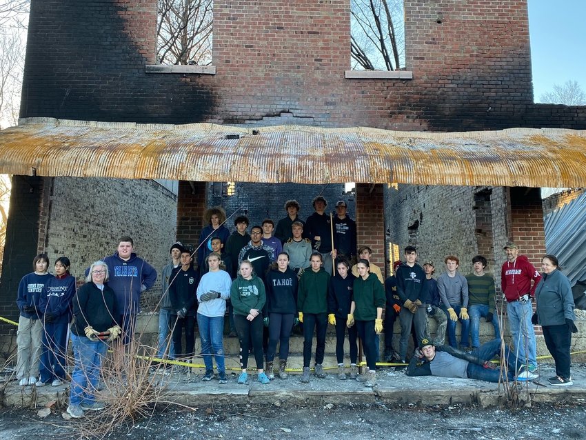 A group of students, parents, staff and alumni of Fr. Tolton Regional Catholic High School in Columbia gathers in front of the charred ruins of a building after helping clear debris from an Oct. 21 fire that leveled much of the town. &mdash; Photo by Tim Scherrer