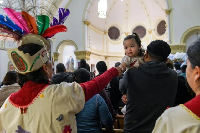 Carmen Maxwell lends her finger and says, &ldquo;peace be with you,&rdquo; to a child eager to participate in the hand-shaking sharing of peace on Monday at Sacred Heart Church in Columbia. This was Maxwell&rsquo;s first time celebrating D&iacute;a de la Virgen de la Guadalupe in Columbia.