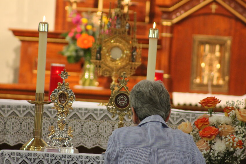 A parishioner adores Christ in the Most Blessed Sacrament, displayed in a monstrance on the altar of St. Stanislaus Church in Wardsville on July 15, in the presence of relics of St. Manuel Gonz&aacute;lez Garc&iacute;a and Blessed Carlo Acutis, who both promoted worship of Christ in the Eucharist, as part of an eight-day prayer vigil in the diocese.