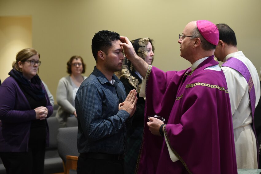 Bishop W. Shawn McKnight and Deacon Enrique Castro distribute ashes to diocesan Chancery employees during Mass on Ash Wednesday.