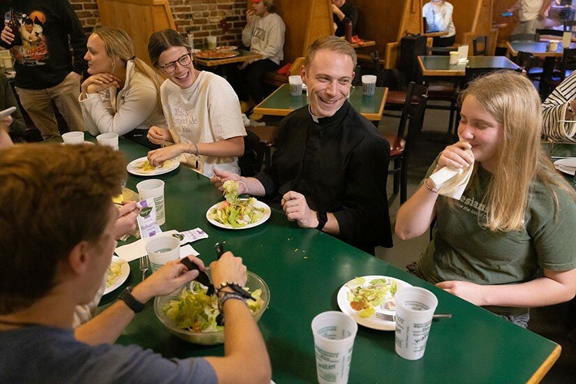 Father Andrew Auer&rsquo;s ministry at the University of Missouri frequently leads him to socialize with students. Father Andrew Auer shared a meal at Shakespeare&rsquo;s Pizza in Columbia with University of Missouri students, from right, Olivia Evers, a parishioner at Assumption in south St. Louis County; Julia Boessen, a parishioner at Sacred Heart in Troy; and Abby Obert, at parishioner at Immaculate Conception in Dardenne Prairie.