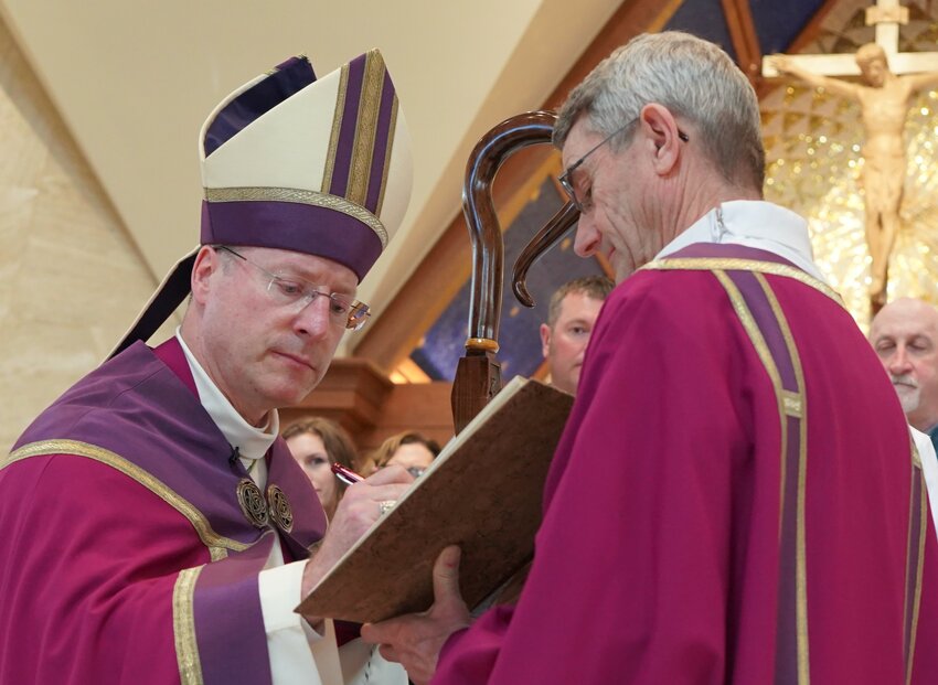 Bishop W. Shawn McKnight signs the Book of the Elect, containing the names of all the people seeking to be baptized at the Easter Vigil in parishes throughout the Jefferson City diocese, during the Rite of Election and Call to Continuing Conversion, held on the First Sunday of Lent in the Cathedral of St. Joseph.