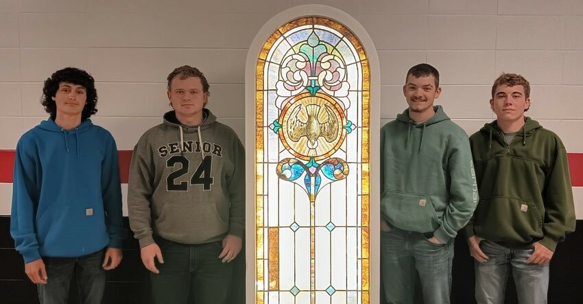 Krayden Hamlin, Robert Dooley, Collin Hayes and Reice Miller stand with the stained glass window they helped restore from the former St. Aloysius Church in Baring. The window is on display in the Baring Community Center.