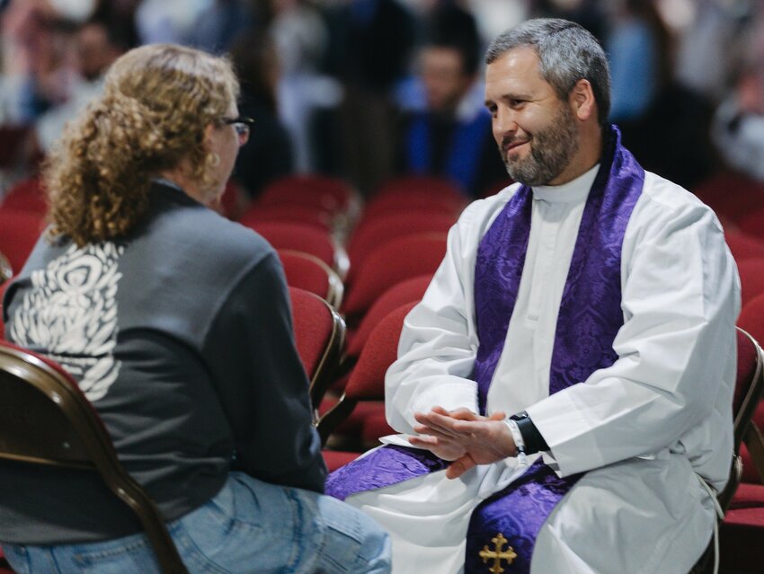 A priest offering the Sacrament of Reconciliation listens to a young woman at the SEEK25 conference in Salt Lake City earlier this year.