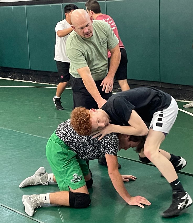 Coach Drake Enloe looks on as Gavin Hall (top) and Drew Carter grapple at a recent practice.