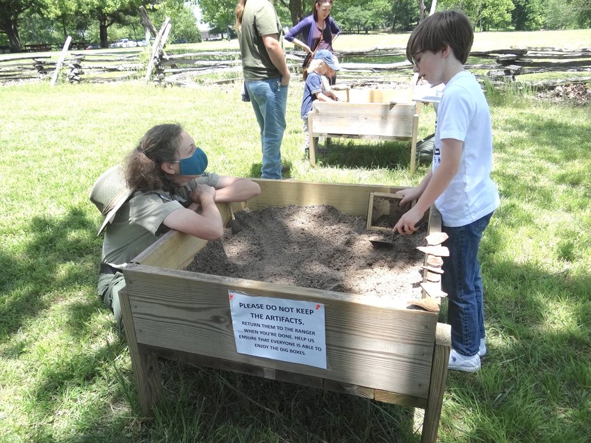 A Chief Vann House staffer explains digging techniques to a young visitor to the park. The next Archeology Day at the Vann House is planned for May 21 from 10 a.m. to 4 p.m.