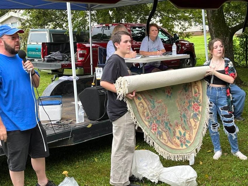 David McDaniel, left, auctions a carpet at the Spring Place Community Festival on Saturday. His assistants are (from left) Ava Ellis and Emma McDaniel.