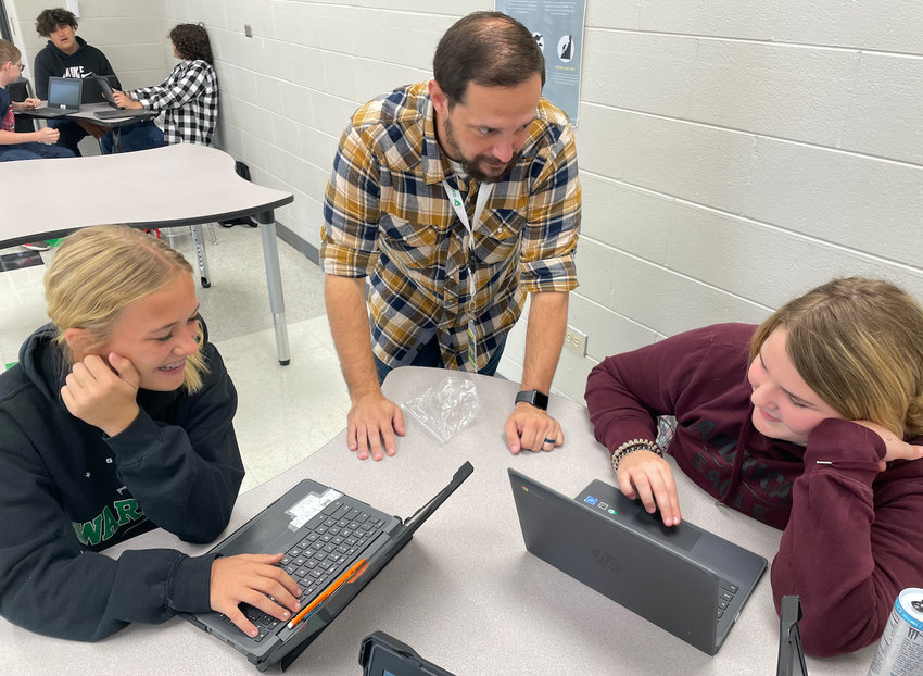 Gladden Middle School students Amelia Huffmen , left, and Michaelynn Keener, right, work together to write a script in their visual arts class. Teacher Cody Cox offers instruction.