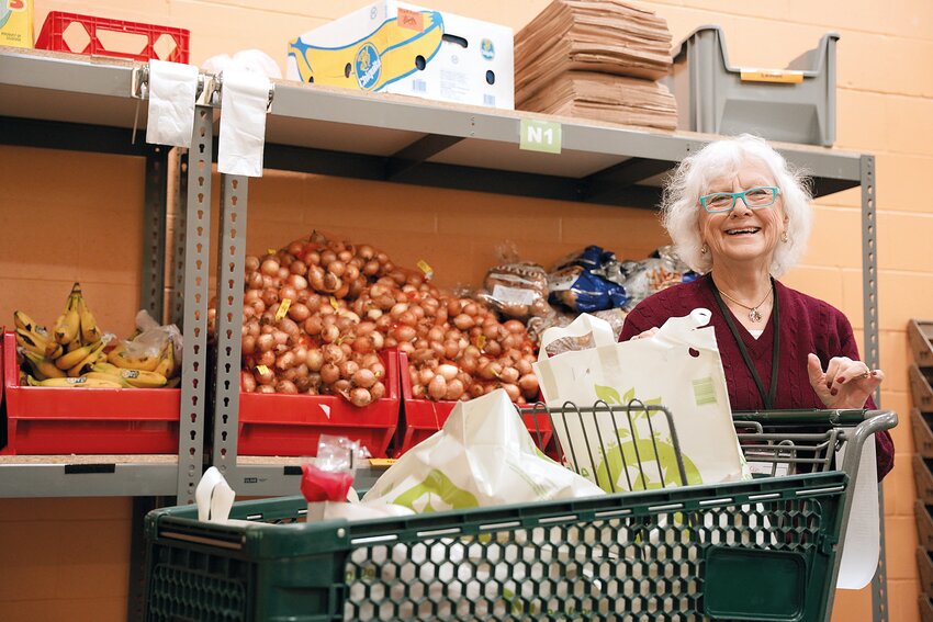 Volunteer Susan Scangas, of Gloucester, packs groceries last month before The Open Door started “live” meals at its newly renovated facility in Gloucester.