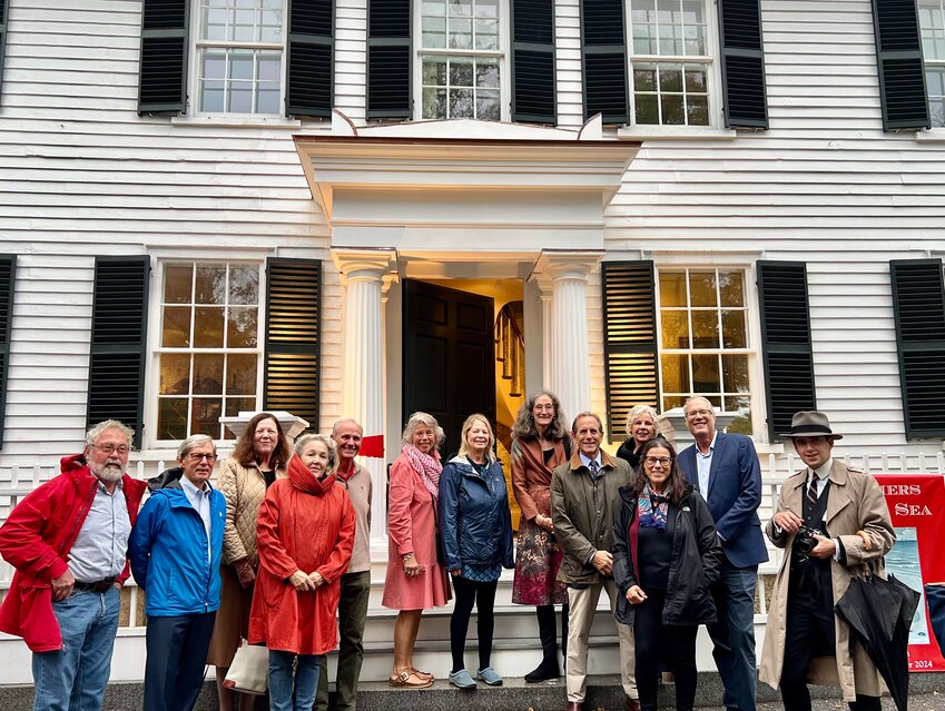 A strong showing of the Manchester-by-the-Sea Museum board braved the rain last Thursday for the official ribbon cutting of the museum’s new portico, which restored an original exterior element of the Trask House that had been missing for more than 100 years.  From left, board members Axel Magnuson, David Lumsden, Suzanna Thompson, Rebecca Campbell, John Round, Marianne Coons, Mary Minott, Carol Bundy, Tom Durken (museum president), Constance Leahy, Alison Anholt-White, Matt Genta, and museum associate director Matthew Swindell.