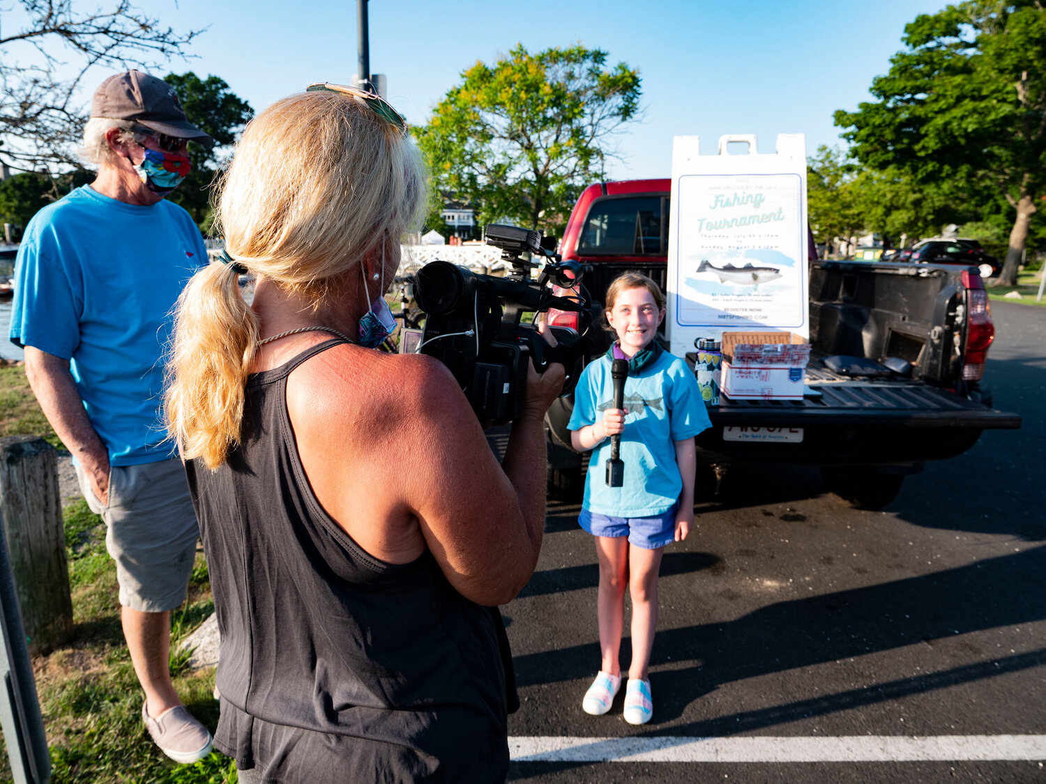 Lily Berkowitz, 10, interviewed by Liz Brown Swanson as part of a television documentary on the history of the Manchester Fishing Tournament.  At this moment, she is telling the story of catching a 40-inch striped bass with her grandfather, David Baer.  A true angler, she withheld the exact location of her catch.