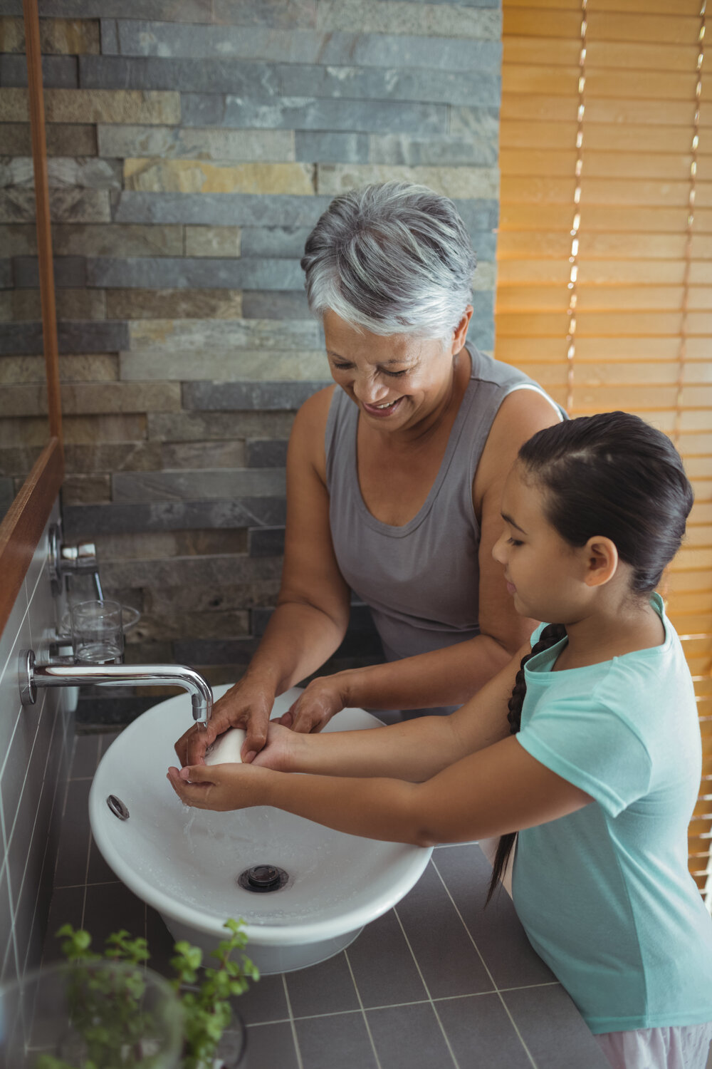 Grandmother and granddaughter washing hands in bathroom sink at home, Coronavirus hand washing for clean hands hygiene Covid19 spread prevention.