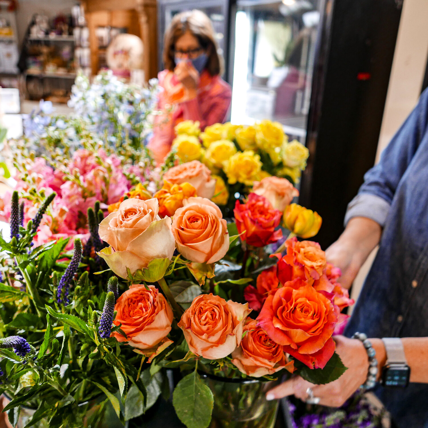 Colleen Malik and Karen Juel Hatch prepare fresh cut flowers at Chapman’s Greenhouse in Beverly Farms.  This time of year, the shop gets flower deliveries every day, and this one was all local, with bright, fluffy orange tulips from Groveland, Massachusetts in front.  This is a busy season for the team at Chapman’s, with gardeners racing to prep their outdoor spaces for planting and—as seen here—preparations for Mother’s Day gifting at a peak.