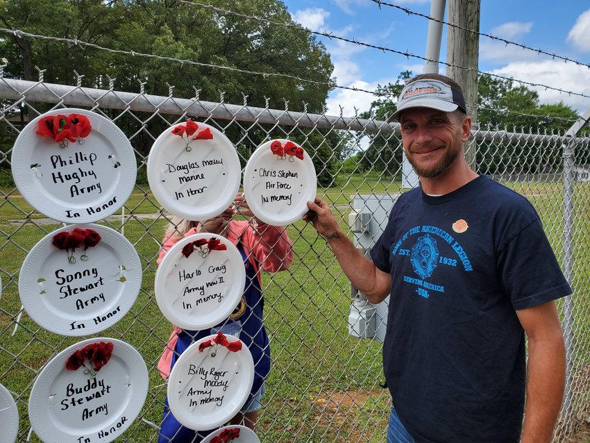Blake Heath, Sons of the American Legion commander, holds a plate in memory of Chris Stephan last year. The Poppy Honor Wall will return this year and be displayed over Memorial Day Weekend on the American Legion Carl Boyd Post 42&rsquo;s fence alongside Martin Luther King Jr. Drive in Cartersville.