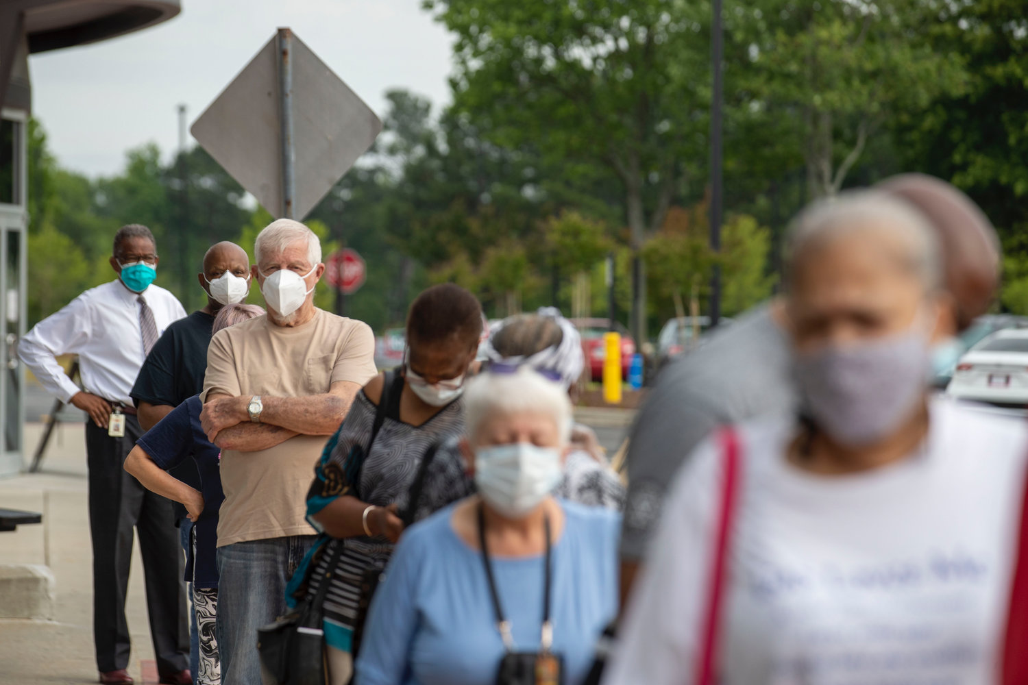 Voters wearing face masks stand in line outside of the Gwinnett County Voter Registration and Elections Office in order to participate in early voting in Lawrenceville on Monday.