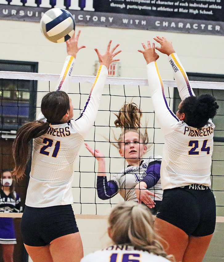Bears senior Emma Cada, middle, spikes the ball through the block attempts of Halle Thompson, left, and Madi Mitchell on Tuesday at Blair High School.