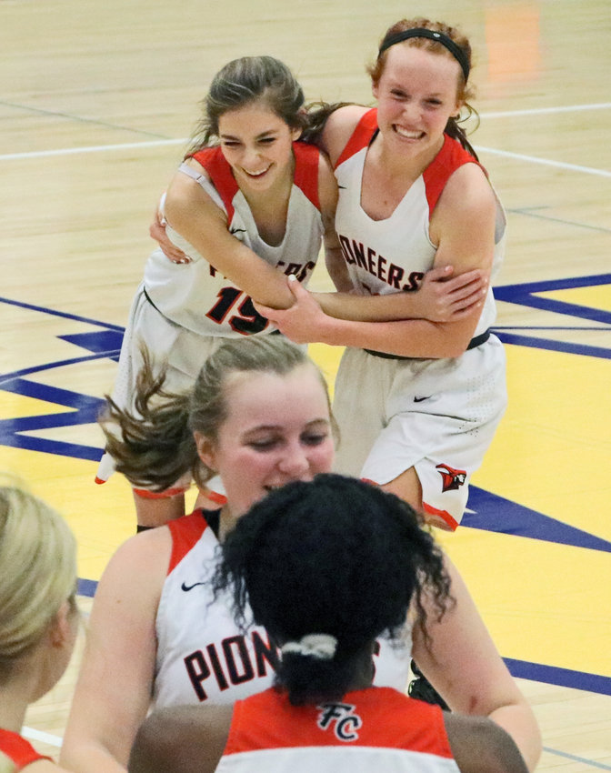 Fort Calhoun's Tess Skelton, back left, and Abbie Anderson embrace, celebrating Monday's subdistrict tournament victory at Wahoo High School. The Pioneers defeated Omaha Concordia 50-47.