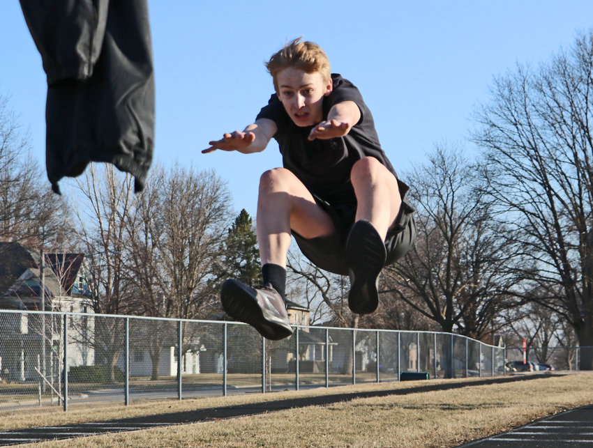 Freshman Kaden Foust leaps toward a marker March 5 during long jump practice at Arlington High School.