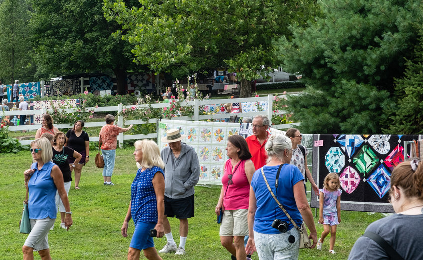Visitors leisurely stroll through the farm yard featuring quilt displays Saturday at Doug and Teri Wolfe's farm.
