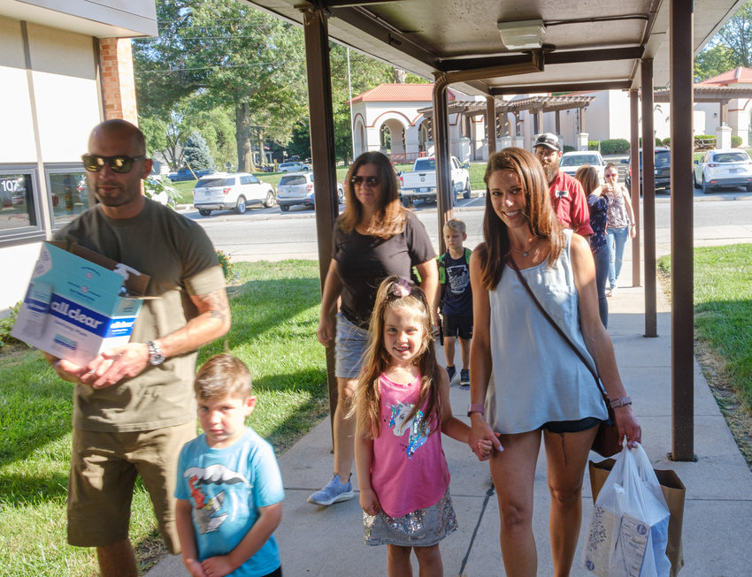 Student and parents with school supplies in hand enter South Primary School on back-to-school night on Monday.