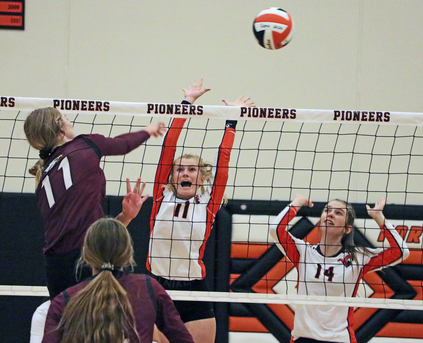 Arlington senior Chase Andersen, left, spikes the ball over the Pioneers' Olivia Quinlan, middle, and Ellie Collins on Thursday at Fort Calhoun High School.