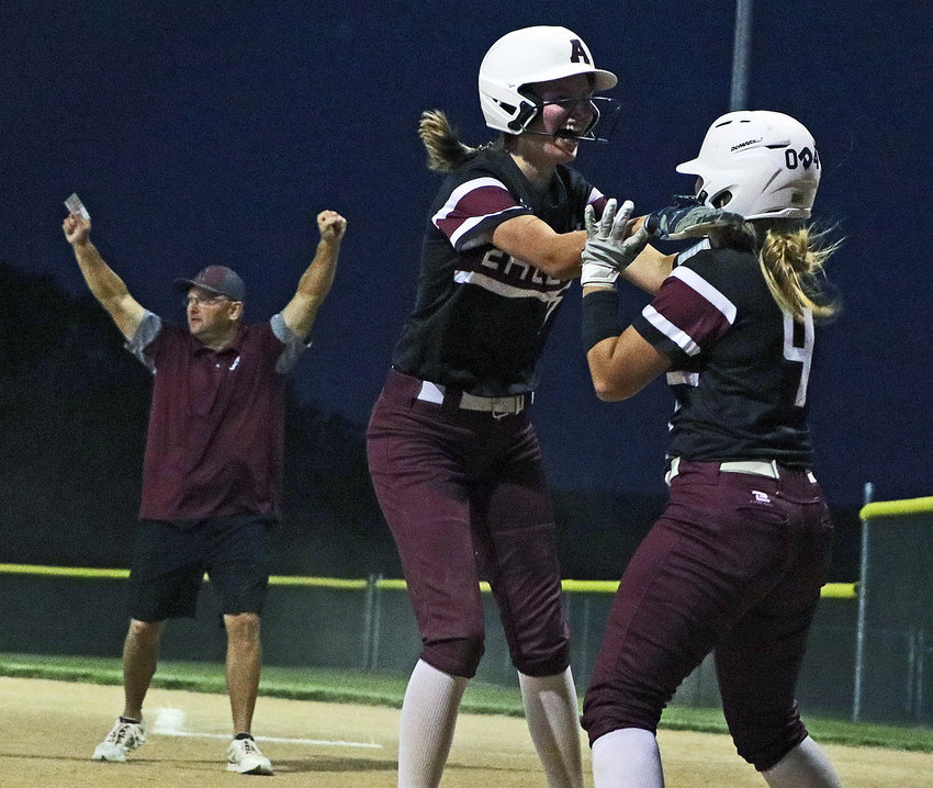 Arlington base runners Britt Nielsen, middle, and Bailey Taylor celebrate a walk-off win as first-base coach Luke Brenn does the same Tuesday at the Two Rivers Sports Complex.