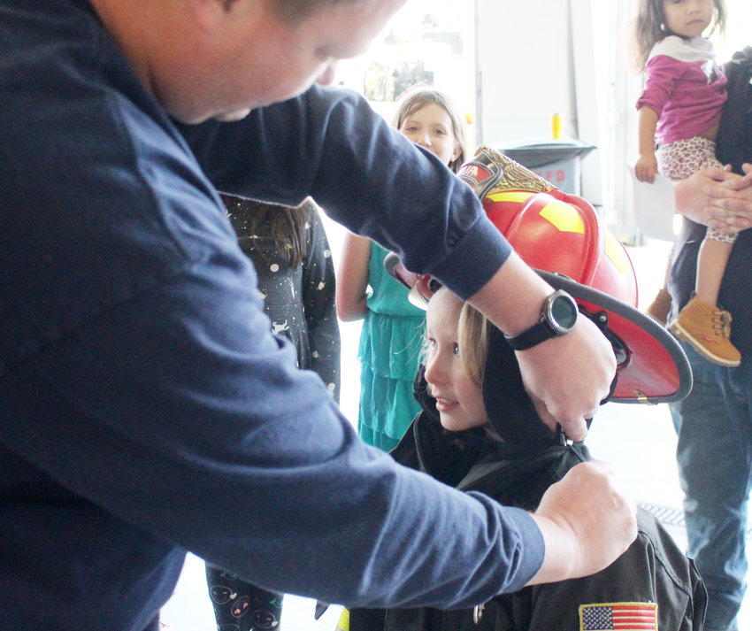 Penny Pickell tries on firefighter gear with help from Randy Backman on Saturday at a fire prevention open house at the Blair North Fire Station.