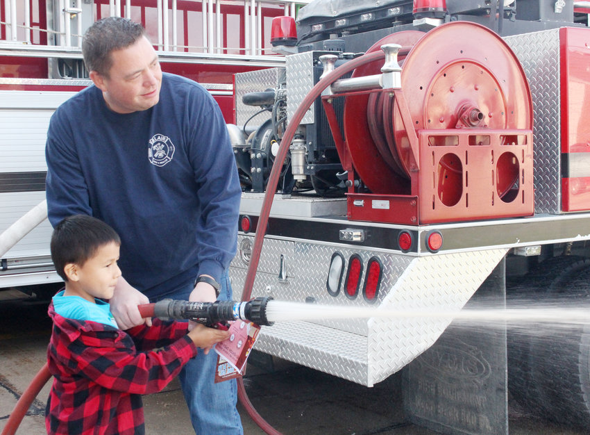 Firefighter Randy Backman helps Jo Pickell, 6, use a fire hose Saturday during a fire prevention open house at the Blair North Fire Station.