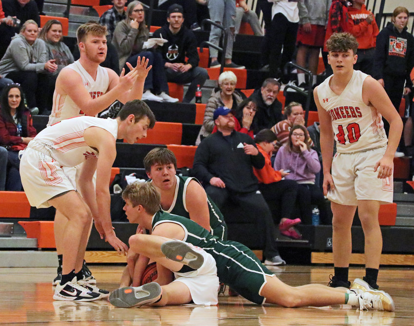 The Pioneers' Grayson Bouwman gets down on the floor to battle Syracuse Rockets for possession of a loose ball Saturday at Fort Calhoun High School.