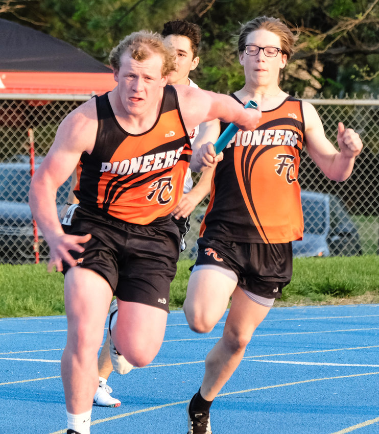 Fort Calhoun senior Clint Dierks, left, takes a 400-meter relay handoff from Michael Maxon on Tuesday at Wahoo High School.