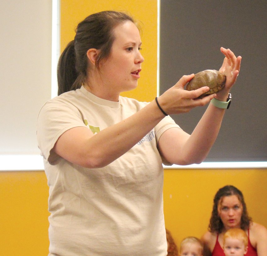 Kaylyn Kelley, Papio-Missouri River Natural Resources District natural resource educator, demonstrates how a box turle, nicknamed Gramps, gets its name by shutting itself into its shell.