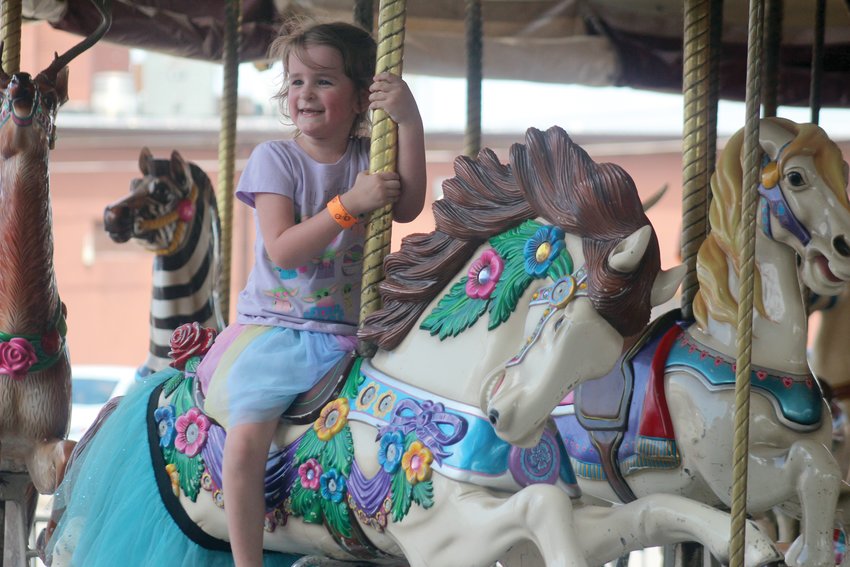 Meadow Winz, 5, smiles as she rides the merri-go-round during Gateway to the West Days Saturday afternoon.