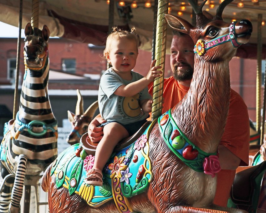 Layla and her dad Colton Harper ride a carnival carousel Friday in Blair.