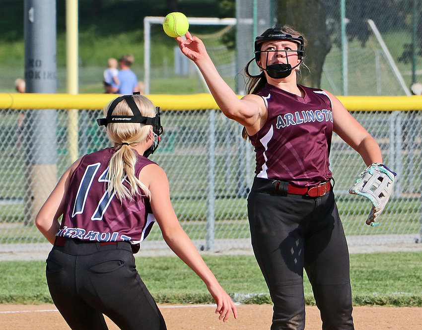 Arlington 12U third baseman Chloey Keen, right, throws the ball to first base over teammate Jaydee Overholt on June 10 at the Blair Youth Sports Complex.