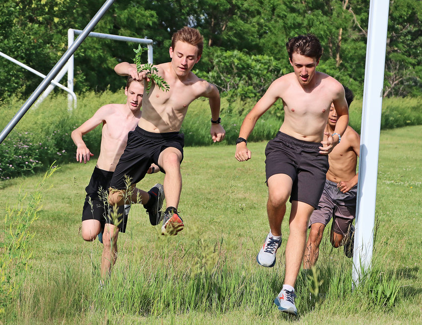 Michael Amandus, from left, Zach Anderson, Jacob Lamoureux and Zeke Prochaska run through a soccer goal frame Tuesday during the Blair High School Cross-Country Clinic.